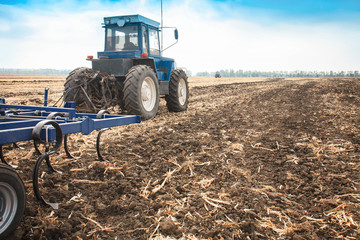 Blue tractor in the field on a sunny day.