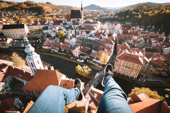 Young person dangling feet high above Cesky Krumlov, Bohemia, Czech Republic