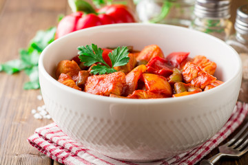 Turkey stew with bell peppers, green beans and tomatoes in bowl on dark wooden table