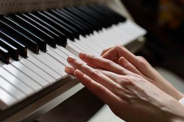 Playing on the synthesizer close-up. women's hands on the keys