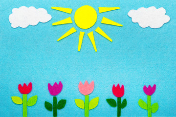 Kolorowa dekoracyjne tło wykonane z filcu przedstawiające świecące słońce, chmury i tulipany, miejsce na tekst. 