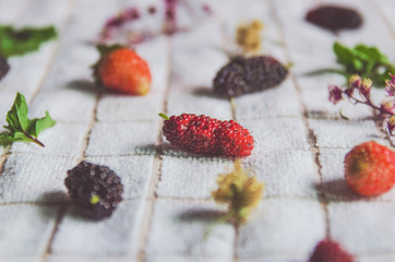 Close-up of mulberry fruit and strawberry, Fresh berry fruit and mint on white fabric.