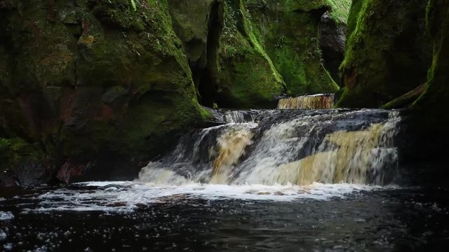 full view of the waterfalls cascading through the devils pulpit gorge in scotland