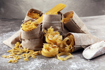 Various mix of pasta on grey rustic background. Diet and food concept.