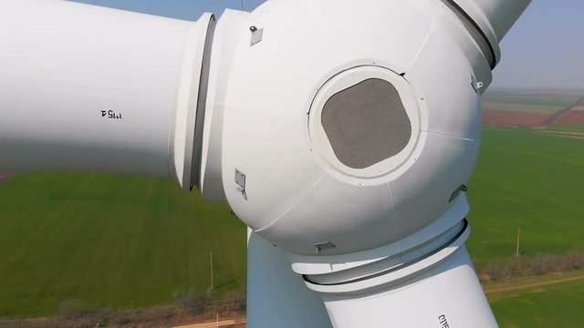 Aerial view of a rotating wind generator in a green field during the day. Electricity generation. The drone flies by next to the turbine. The windmill is close-up. Modern technologies.
