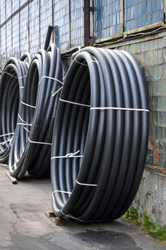 Coiled black plastic pipes stored outdoors