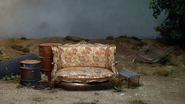 Gold settee next to rusty oil barrels