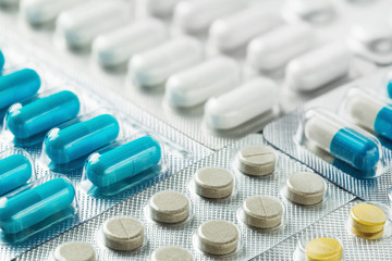 Heap of medical pills in white, blue and grey. Pills in plastic package. Concept of healthcare and medicine.