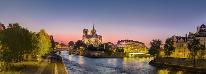 Panoramic view of Notre Dame (famous Paris landmark) along the Seine river at twilight, sunset,...
