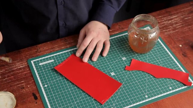 The artisan in the workshop glues the leather blanks, making the leather product