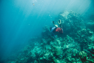 Fototapeta na wymiar Man diving snorkeling on reef stone with fish in sea