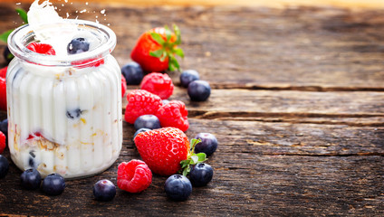 Yogurt with berries and cereals - healthy breakfast on wooden table