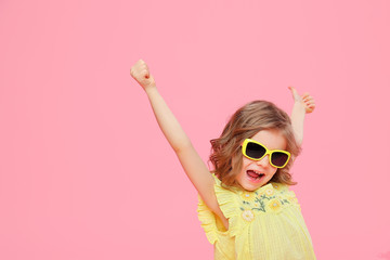 Excited expressive Wonderful happy girl in yellow dress and sunglasses holding hands up in great...