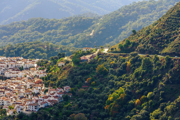 Green landscape with cloudy sky and small town among mountains in Andalusia, Spain