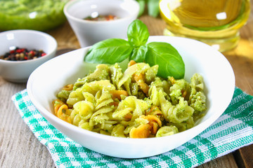 Pasta with pesto sauce on an old wooden table.