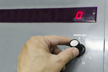 Hand on manual speed regulator button on industrial offset printing machine