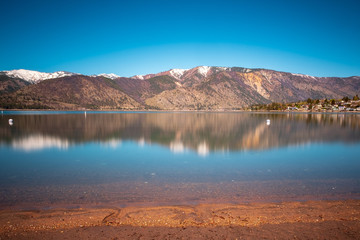 A long exposure of Lake Chelan shows off vibrant blue skies and reflections of the snowcapped mountains