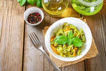 Pasta with pesto sauce on an old wooden table.