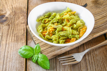 Pasta with pesto sauce on an old wooden table.