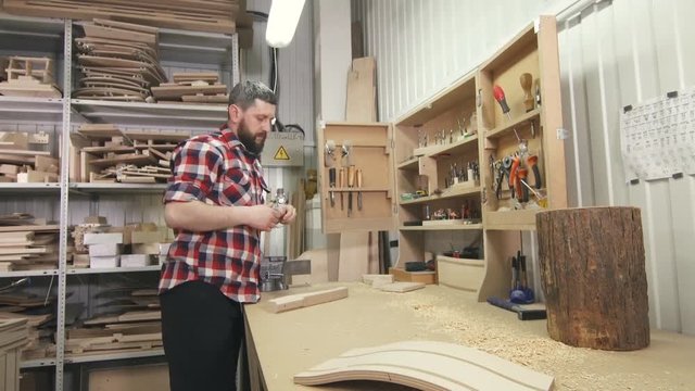man carpenter in a shirt with a beard uses tools in the workshop