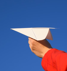 White paper airplane in hand against the sky. A symbol of freedom on the Internet.