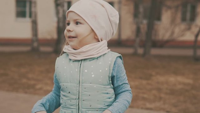 Happy little girl dances in city square in slow motion.