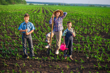 Smiling kids standing with shovel on green field