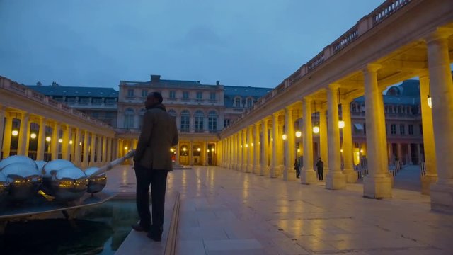 Man with umbrella in Royal Palaice of Fontainebleau in France at twilight. The Royal Palace of Fontainebleau was one of the main palaces of French kings