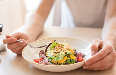 Young boy eating vegetable salad with roast beef in restaurant. Life style