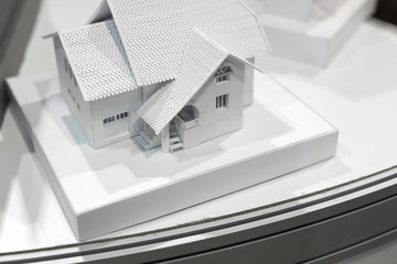 architecture, design, infrastructure concept. close up of small white cardboard model of the house with two floors, elegant windows in classic style, two step roof with tile