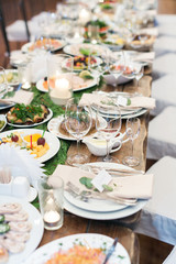 feast, dining, food concept. there is table that is waiting guests, it is almost prepared for celebrating, covered with tasty dishes, souces, snacks, but glasses are still empty
