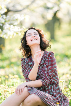plants, happiness, emotions concept. in the fresh grass there is an dorable woman who is shrieking with laughter, her radiant smile is shining in the bright light of summer sun