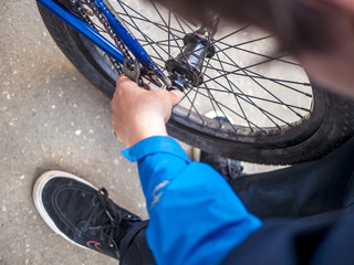 Naklejka premium close up young man rapairing bicycle on the street city