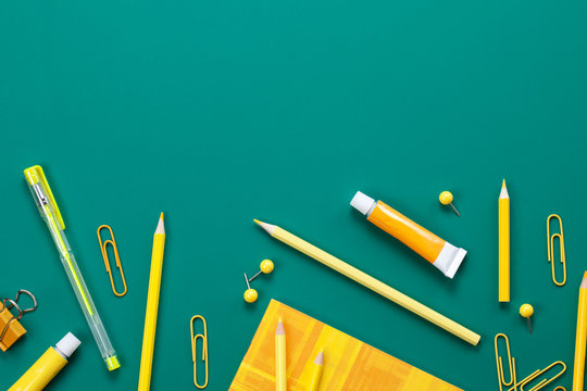 Yellow school supplies over the green board. Education, studing and back to school concept