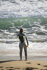 Chica surfista en la playa entrando al mar