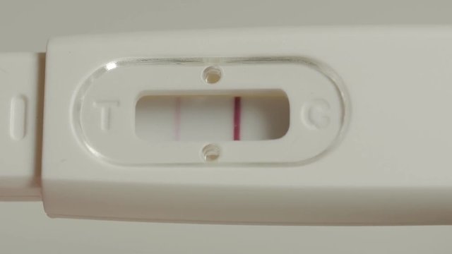 Positive pregnancy test in hands. Extremely close up shot.