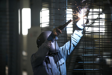 Welder man welds at the factory. Industrial Worker welder welding steel structure for concrete pipe. Industry manufacturing concept