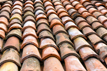 Close-up of old and weathered clay tile roof, pattern of orange tiles