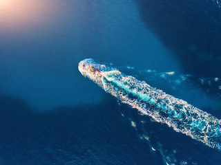 Yacht at the sea. Aerial view of luxury floating ship at sunset. Colorful landscape with boat in marina bay, blue sea. Top view from drone of yacht. Luxury cruise. Seascape with motorboat. Ocean