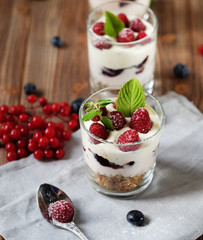Healthy breakfast - yogurt with fresh berries and muesli served in glass jar, on wooden background
