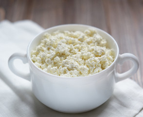Fresh cottage cheese in a  bowl on a wooden table.
