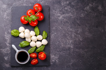 Mozzarella cheese, basil and tomato cherry on slate stone board, copy space. Ingredients for Caprese salad