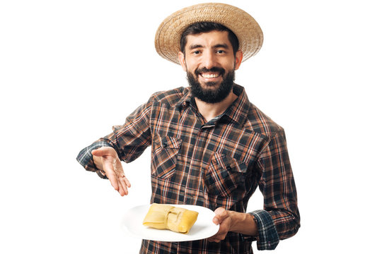 Brazilian man wearing typical clothes for the Festa Junina serving traditional food Pamonha