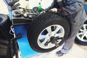 Car mechanic balancing car wheel on computer machine balancer in auto repair service