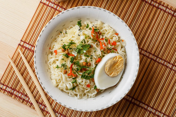 Instant noodles in bowl, Asian cheap fast food on table, top view