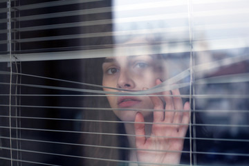 Woman portrait; young woman looking through the window.