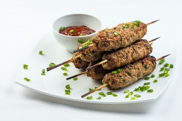 kebab with herbs on a white plate on a white background