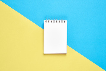 Black screen notebook blank and pen placed on pastel yellow and blue background. Suitable for graphics used for advertising.