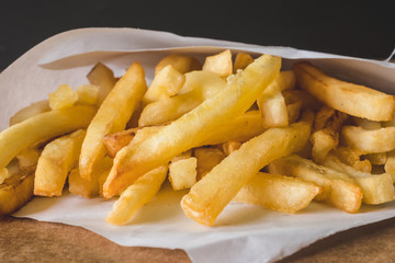Close up of French fries on wooden table.