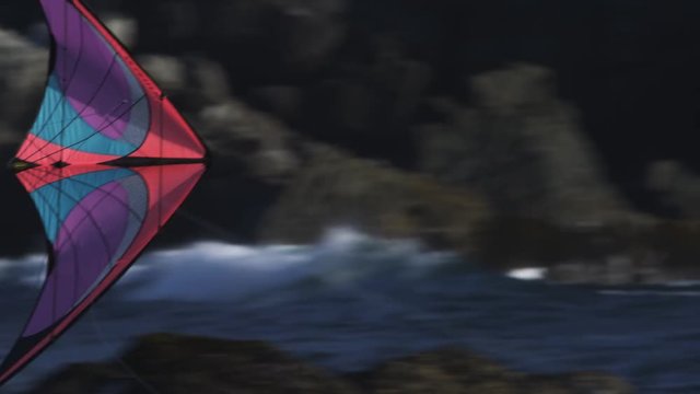 Tracking a colorful kite flying above waves below coastal cliffs